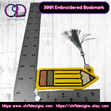 Close-up of an embroidered pencil bookmark with a silver tassel, shown next to a ruler for size reference, highlighting the intricate stitching and vibrant colors