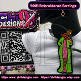 Afro Diva embroidered earring worn on a mannequin, showcasing the detailed design with Chi 9 Designs branding in the background.