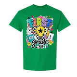 A green short-sleeve crewneck t-shirt featuring a colorful graphic on the front that reads 'FIRST grade' with school-themed doodles including a lightbulb, pencil, notebook, and stars.