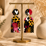 Handmade wood statement earrings displayed on a brass jewelry stand in a luxury boutique setting.