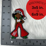 2024 Holiday Diva embroidered patch in red pants and a Santa hat with a ruler showing the size as approximately 3x5 inches.