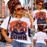 A woman modeling a white graphic T-shirt in an urban street setting, shown in a large front view and two smaller back/side views. The shirt features a bold red, orange, and navy graphic with the words 'BEAR DOWN' and an illustrated figure in a blue jacket.