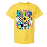 A bright yellow short-sleeve t-shirt with a colorful 'FIRST grade' graphic on the front, featuring school-themed doodles and text, shown against a plain white background.