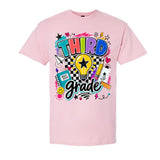 A light pink short-sleeve crewneck t-shirt featuring a colorful graphic print on the front with the words 'THIRD grade' in stylized lettering, surrounded by school-themed doodles like a lightbulb, notebook, pencil, and stars.