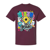 A maroon short-sleeve crewneck t-shirt featuring a colorful graphic on the front that reads 'SIXTH grade' with a lightbulb, pencil, notebook, and other school-themed doodles, shown against a plain white background.