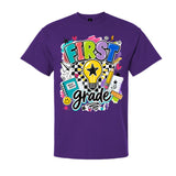 A purple short-sleeve crewneck t-shirt featuring a colorful 'FIRST grade' graphic on the front, complete with a lightbulb, pencil, notebook, and checkered pattern, shown against a plain white background.