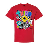 A red short-sleeve crewneck t-shirt featuring a colorful 'THIRD grade' graphic on the front, complete with a lightbulb, stars, hearts, and school supplies, shown against a plain white background.