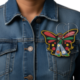 Afro butterfly girl embroidered patch with red, green, and yellow wings attached to the chest pocket of a blue denim jacket, highlighting Afrocentric flair and creative customization.