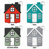 Four small house-shaped keychains shown in different color options: red, teal, salvage green, and grey. Each keychain has a dark roof, white trim, and a white door, with window and door details.