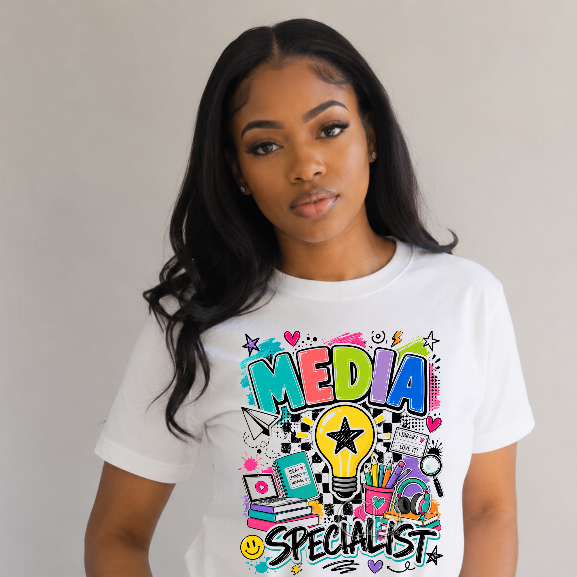 Media Specialist graphic t-shirt worn by a woman featuring colorful books, pencils, headphones, and lightbulb design.