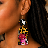 Woman wearing handmade wood statement earrings with colorful abstract artwork and gold ear wires.