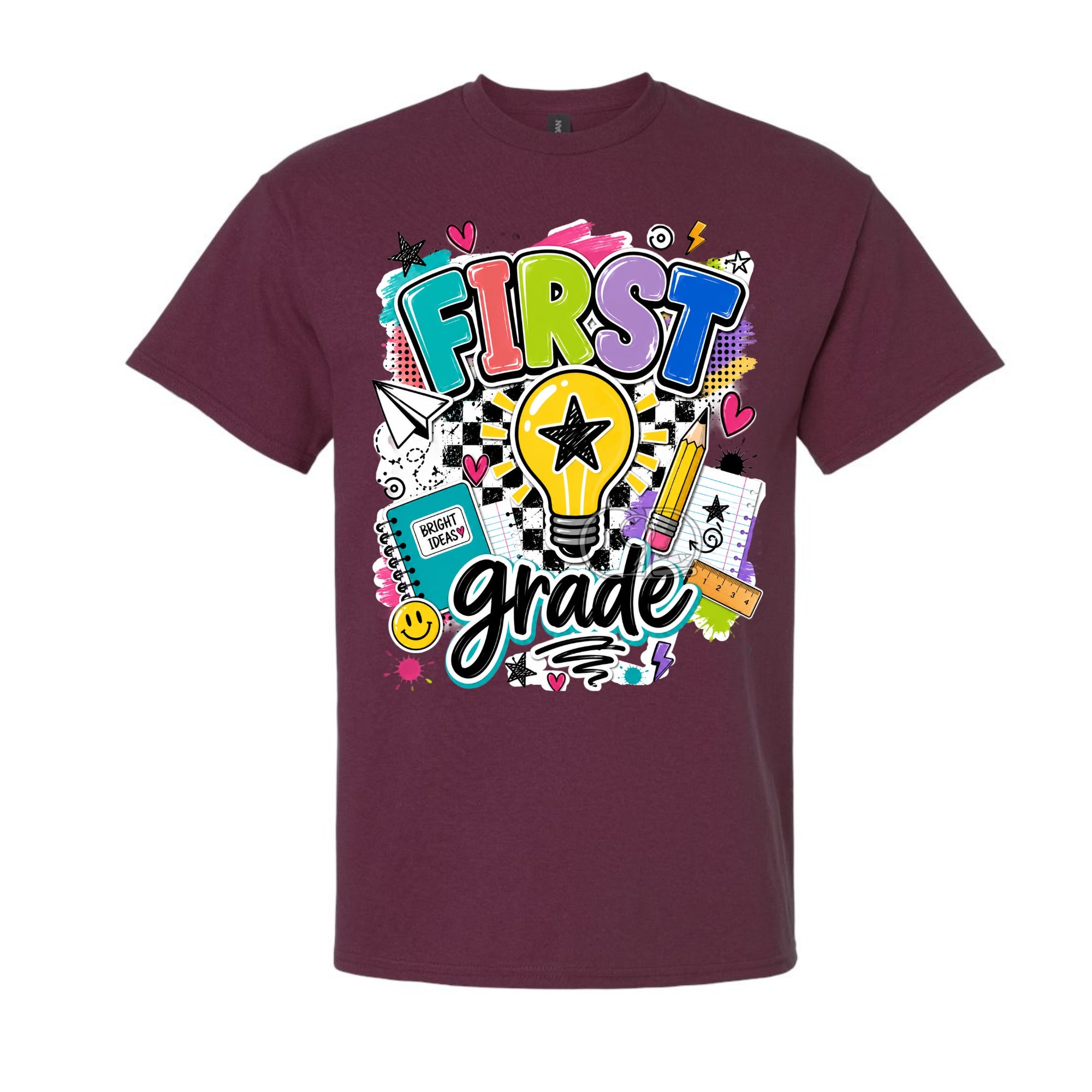 A maroon short-sleeve crewneck t-shirt featuring a colorful 'First Grade' graphic on the front, complete with a lightbulb, pencil, notebook, and checkered pattern, shown against a plain white background.